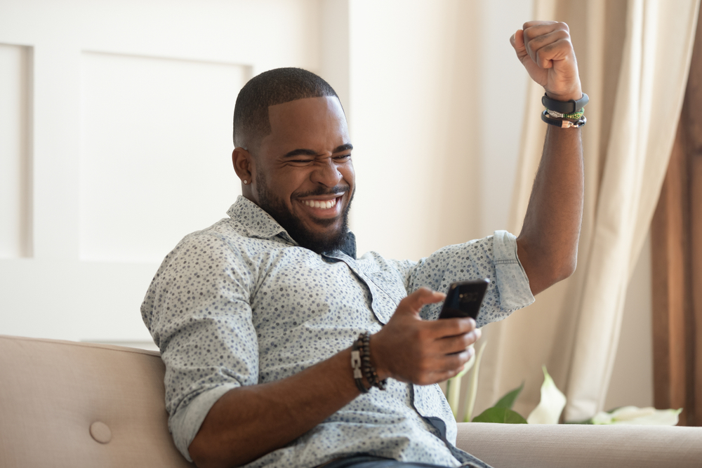 Excited,Overjoyed,Black,Man,Winner,Holding,Smartphone,Feeling,Euphoric,With Nunca aposte com o seu coracao