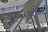Detail, freestanding one story cafeteria building with extended, folded metal sun shading on roof and extensive galvanized steel bracing