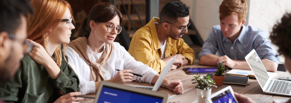 students around a table with laptops