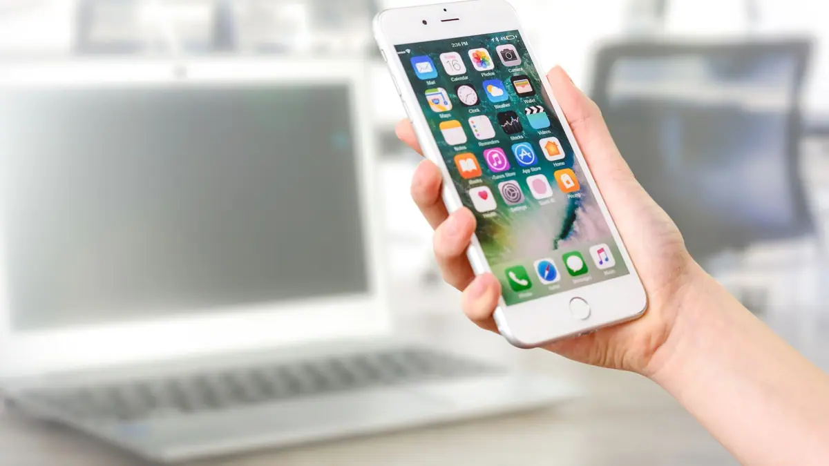 Mão segurando um smartphone com vários aplicativos na tela