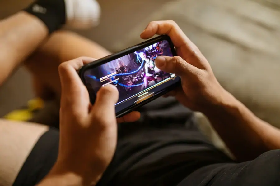 Pessoa jogando no smartphone sentada em um sofá Pessoa jogando no smartphone sentada em um sofá
