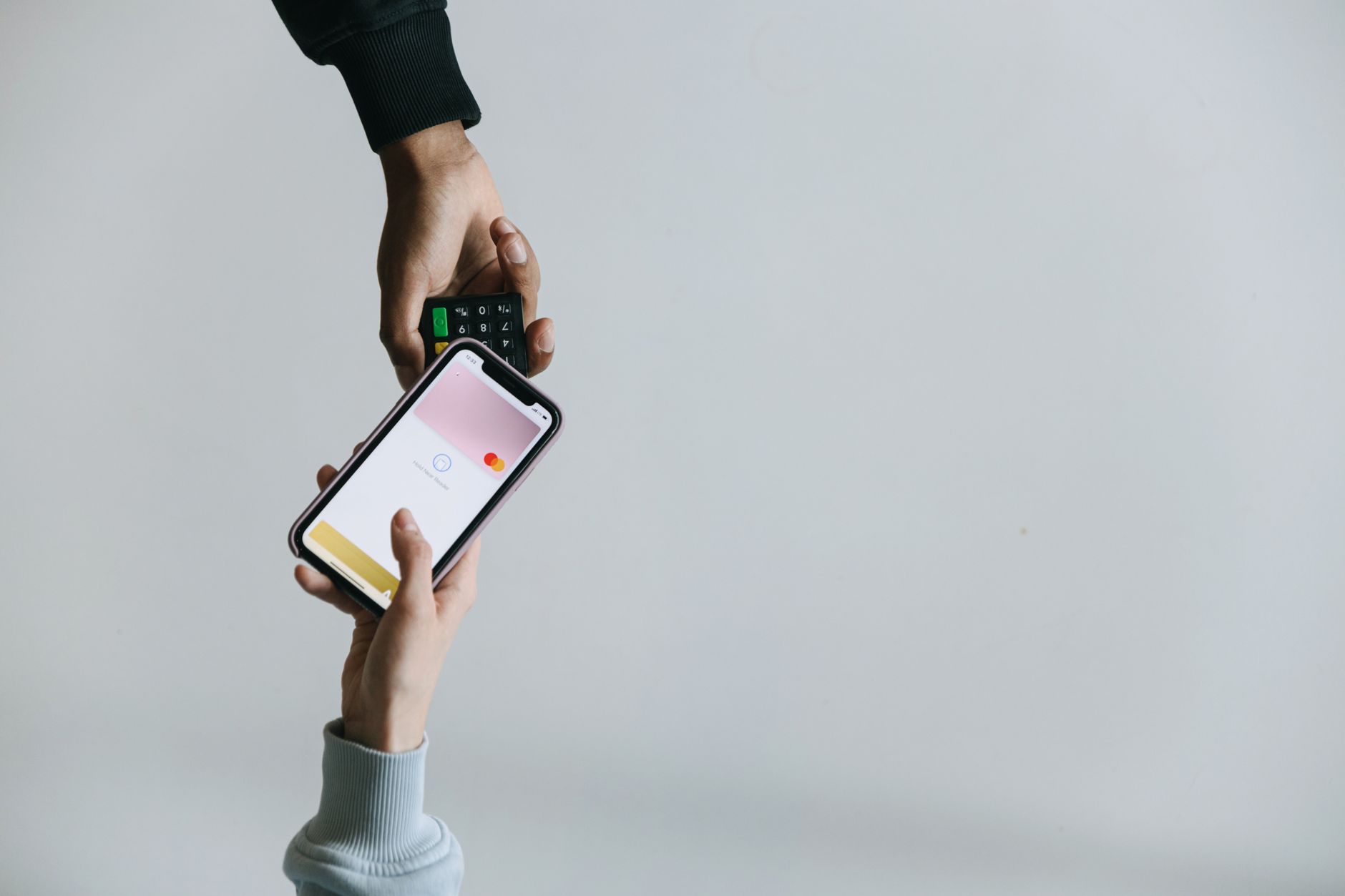 Android ou iPhone: como decidir sem torcida Hands using smartphone and terminal for cashless payment, showcasing modern transaction methods.