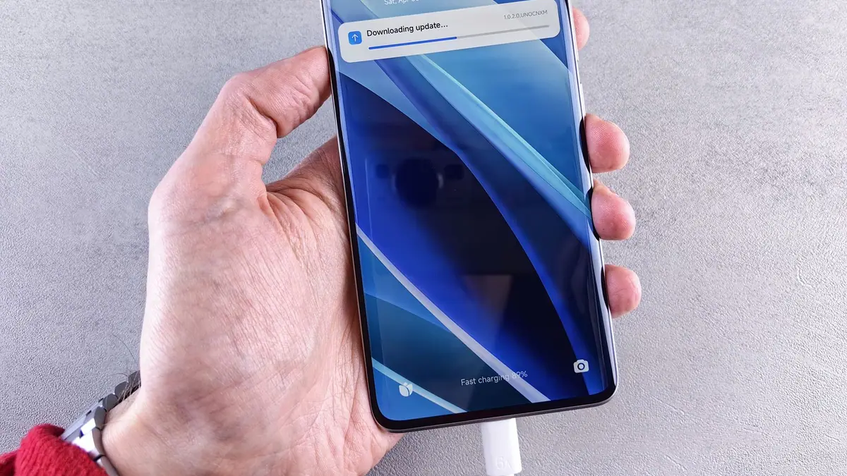 Mão segurando um smartphone com uma notificação de atualização sendo baixada