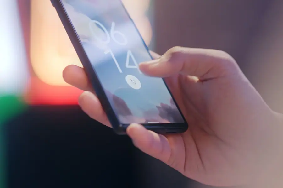 Mão segurando um smartphone com leitor de digital bloqueado Mão segurando um smartphone com leitor de digital bloqueado