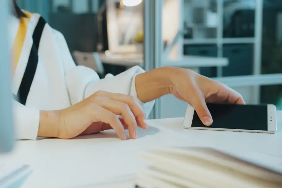 Mão de uma mulher usando o celular em uma mesa de escritório Mão de uma mulher usando o celular em uma mesa de escritório