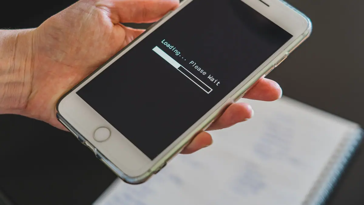 Mão segurando um smartphone com uma tela de carregamento