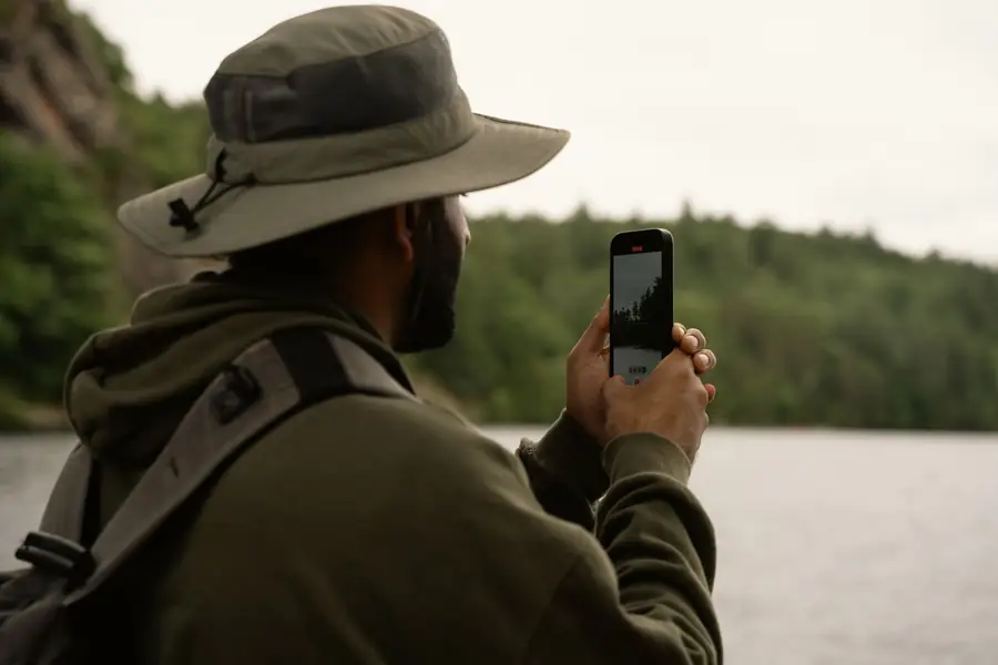 Pessoa ao ar livre fotografando a paisagem de um lago com o smartphone Pessoa ao ar livre fotografando a paisagem de um lago com o smartphone