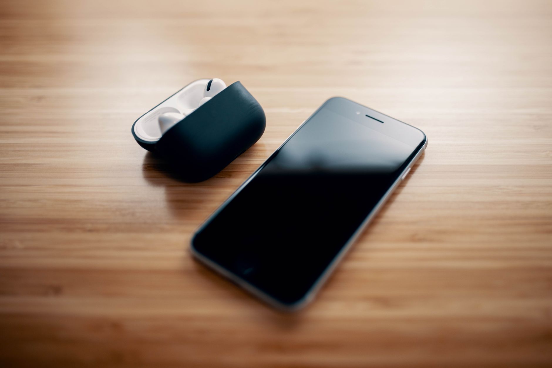 Duas capinhas de celular, uma de silicone e outra rígida, ao lado de um smartphone sobre uma mesa.