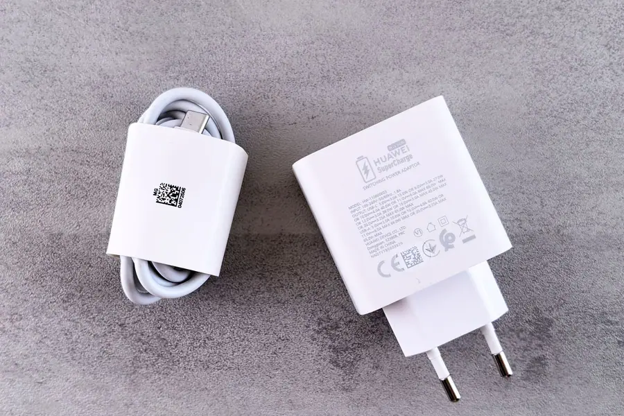 Carregador branco com cabo USB sobre uma superfície cinza texturizada Carregador branco com cabo USB sobre uma superfície cinza texturizada