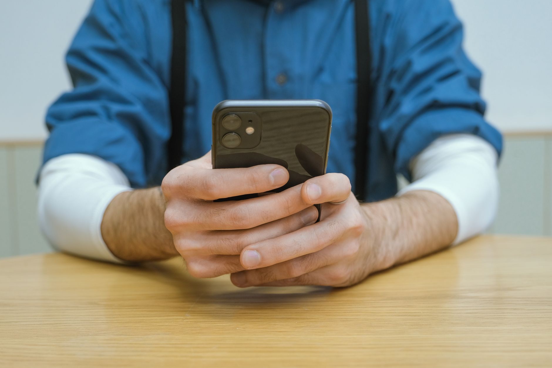 Pessoa comparando dois celulares sobre uma mesa antes de comprar