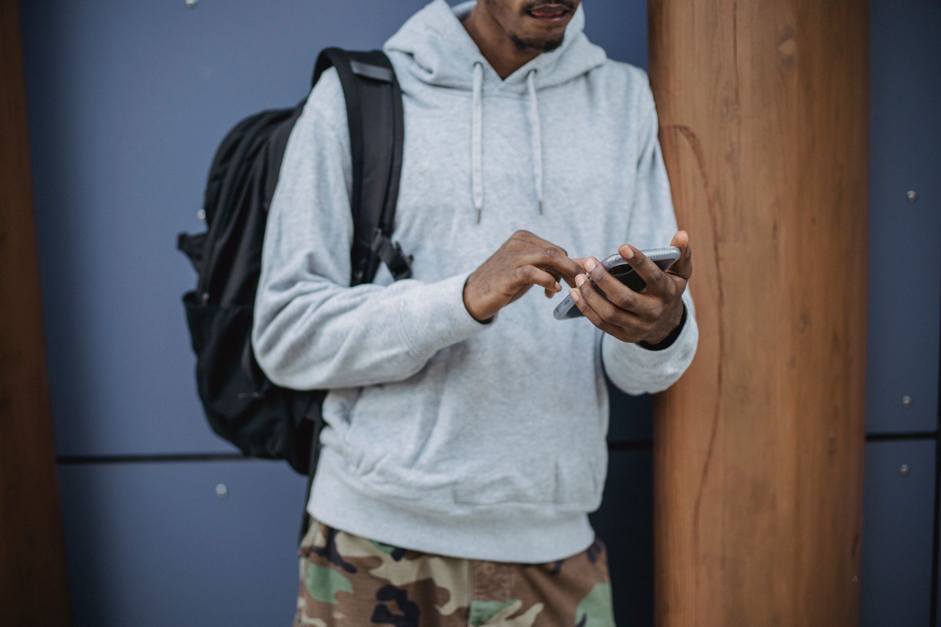 Comprar celular no Paraguai vale a pena? Riscos reais Crop anonymous black male traveler in casual clothes and backpack browsing smartphone while standing on city street during trip