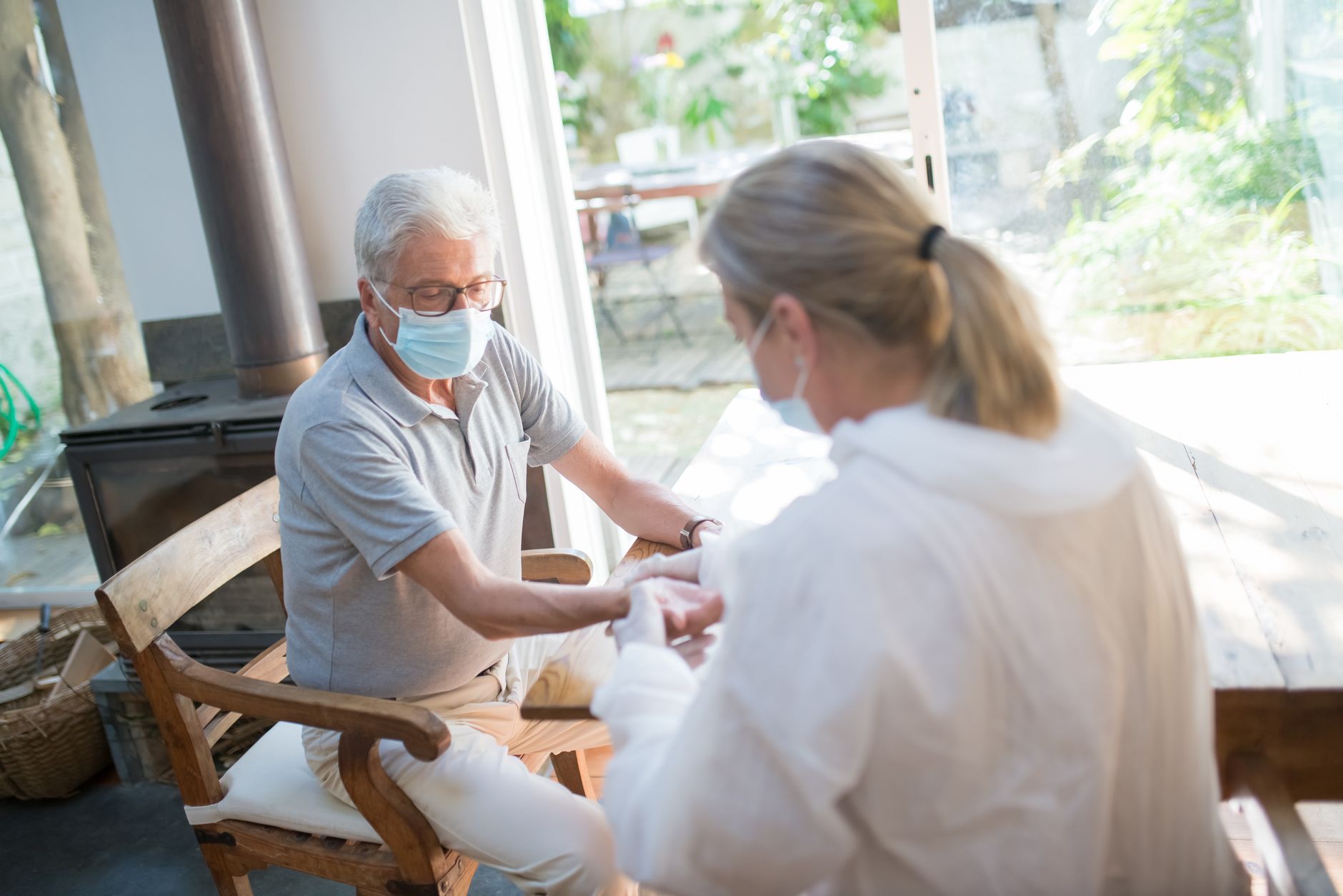 Como escolher celular para idosos: o que priorizar A healthcare worker examining a senior man at home with face masks during the pandemic.