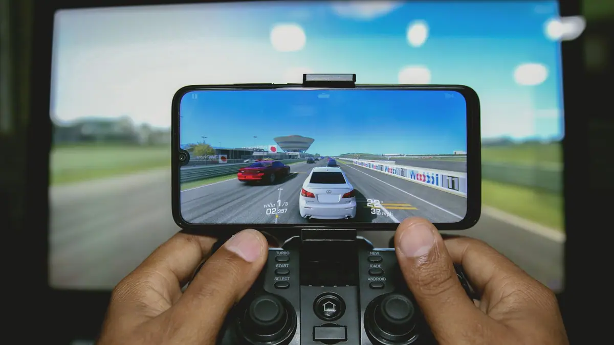 Mãos jogando um jogo de corrida em um celular com controle