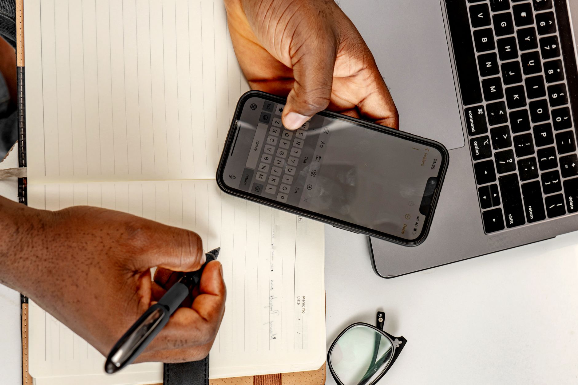 Celular travando e lento: como resolver Business person multitasking with a smartphone and notebook at their desk.
