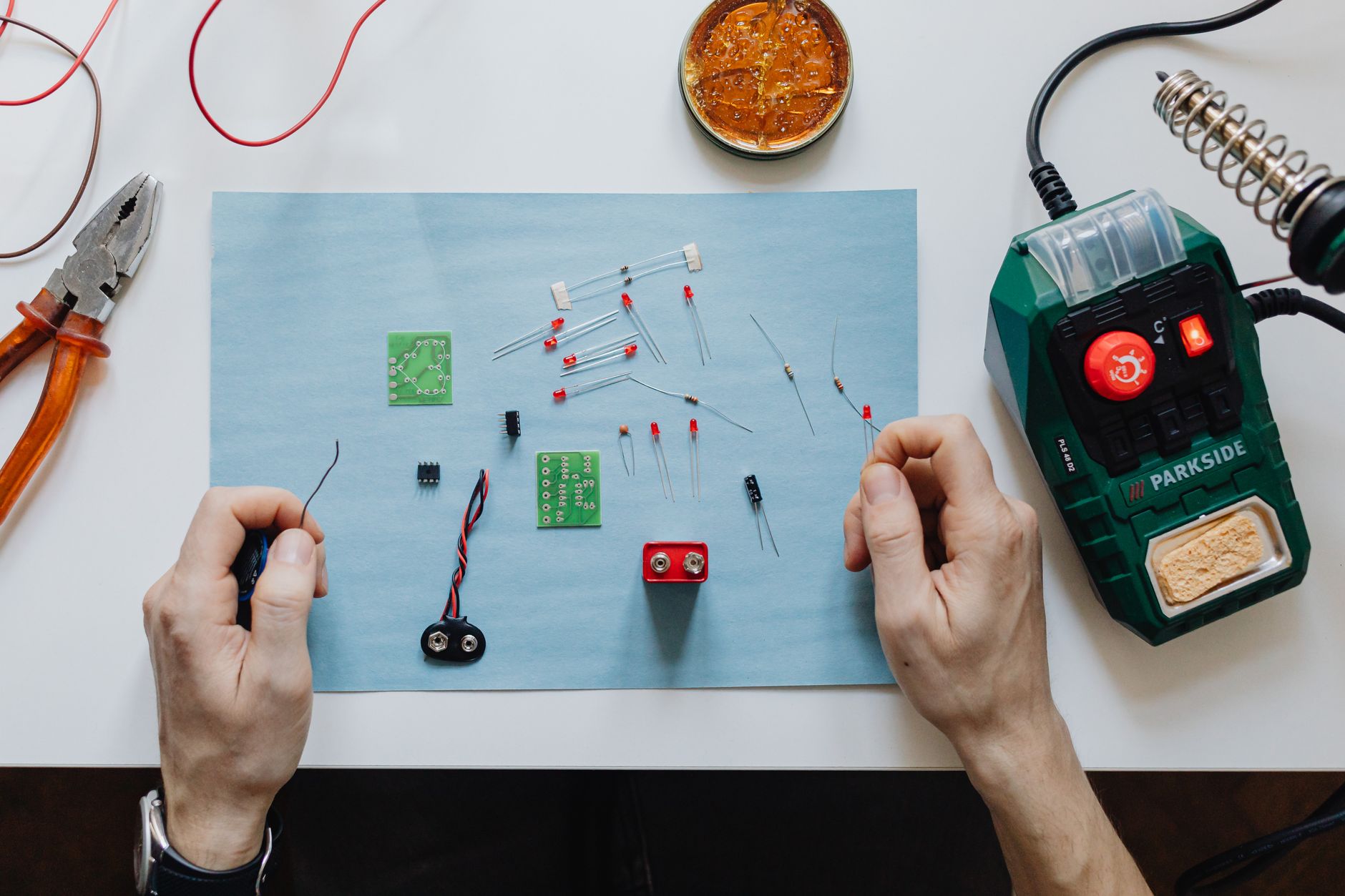 Como avaliar celulares com bateria de silício-carbono Hands-on electronics repair with tools, circuit board, and soldering station on workspace.