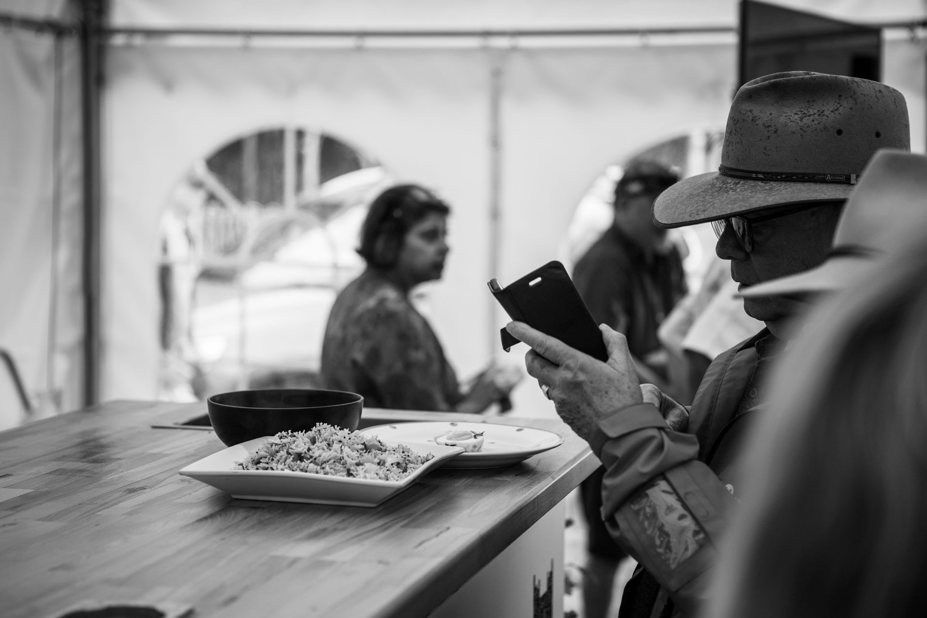 Quais celulares devem chegar ao Brasil em 2026 Black and white image of a meal on a table with people in an outdoor tent.