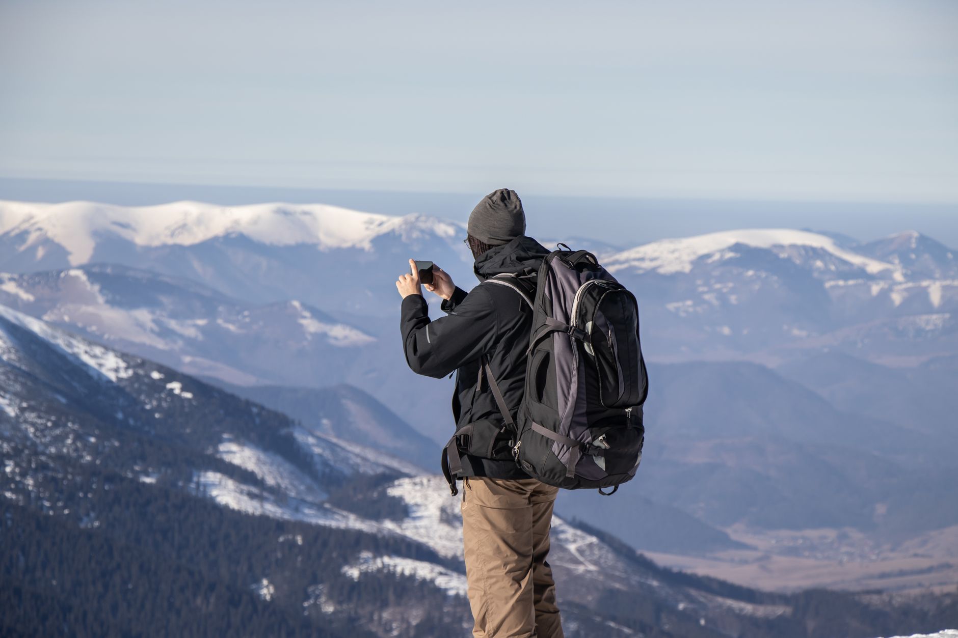 Chip físico ou eSIM: qual escolher? A person capturing the stunning view of snowy mountains with a smartphone.