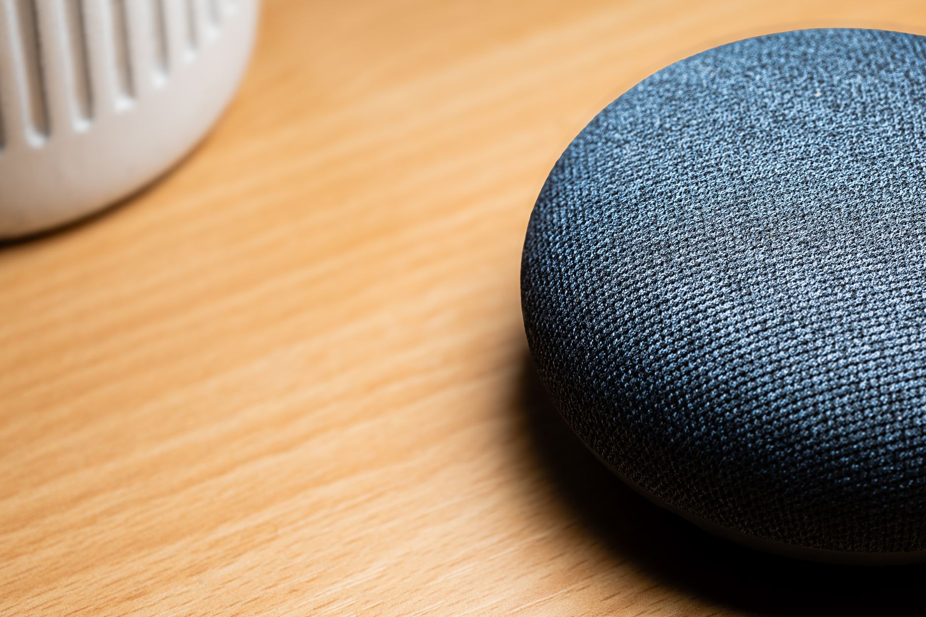Como Aumentar o Volume do Celular Além do Limite Padrão A close-up view of a smart speaker on a wooden table, capturing texture details.