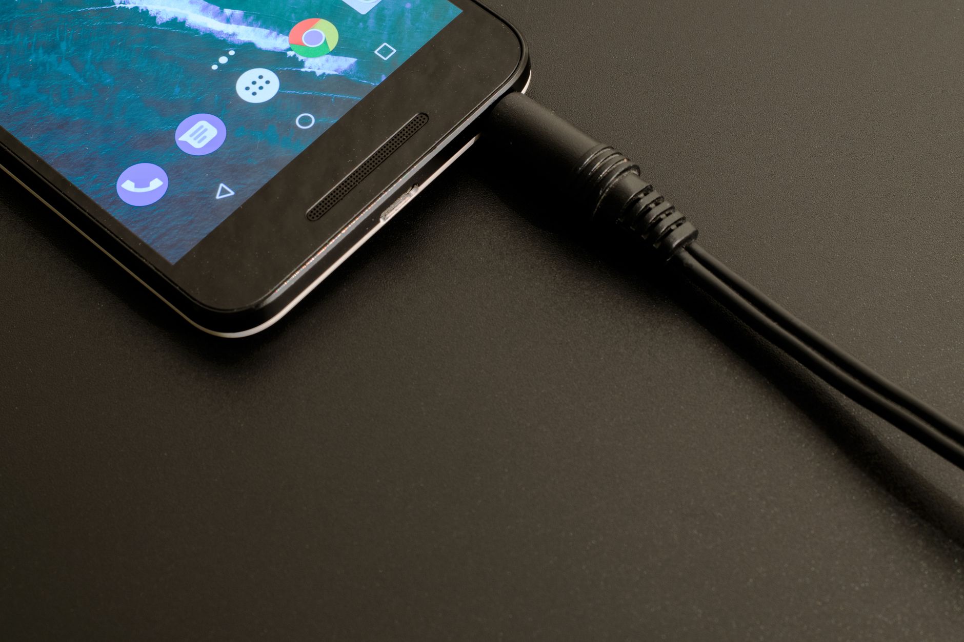 Calibrar a bateria do celular funciona mesmo? Close-up of a smartphone being charged, displaying a modern interface on a dark backdrop.