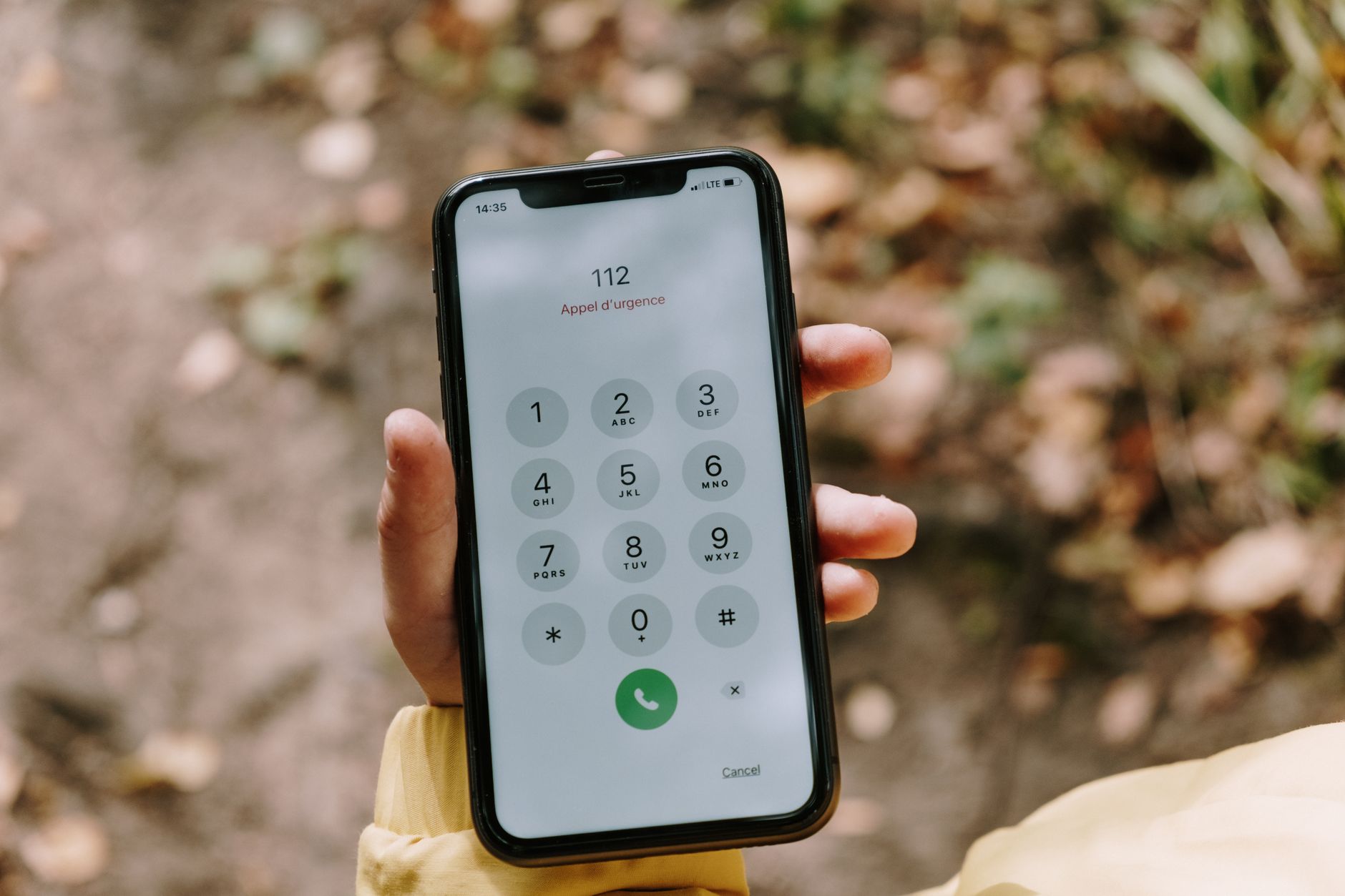 Close-up of emergency number dialed on smartphone held outdoors, emphasizing mobile technology's role in safety.
