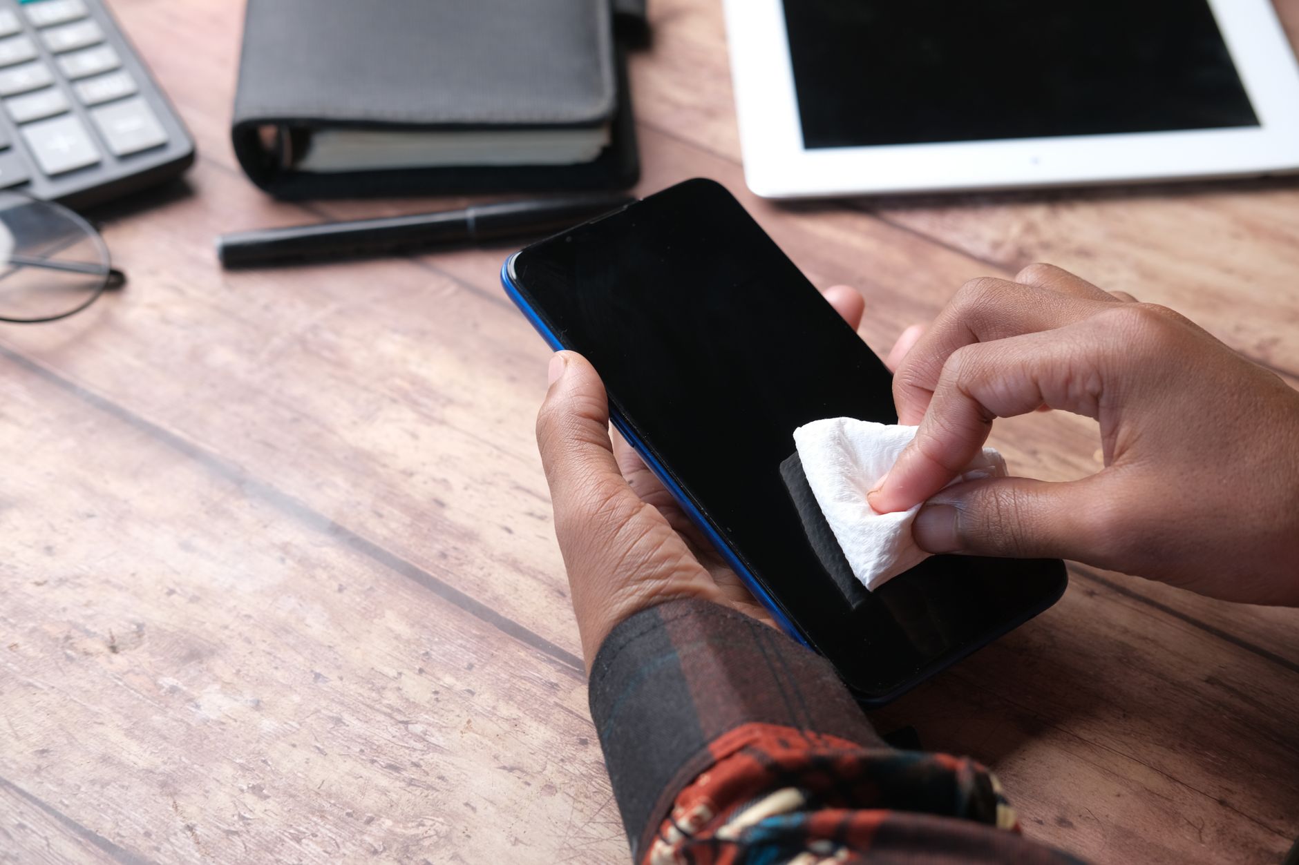 Pessoa limpando cuidadosamente a entrada de carregamento de um celular sobre uma mesa