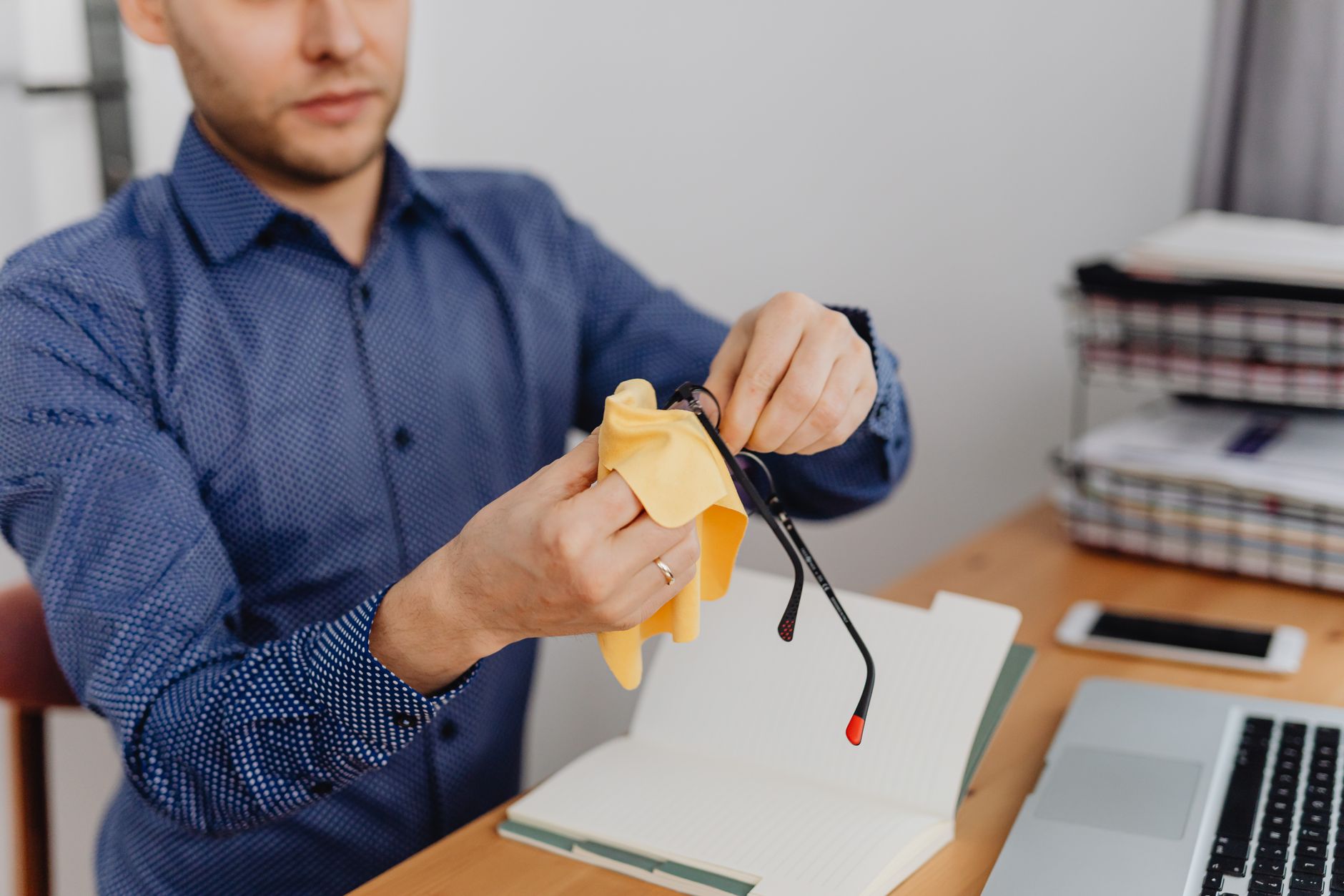 Pessoa limpando a tela de um celular com pano de microfibra sobre uma mesa