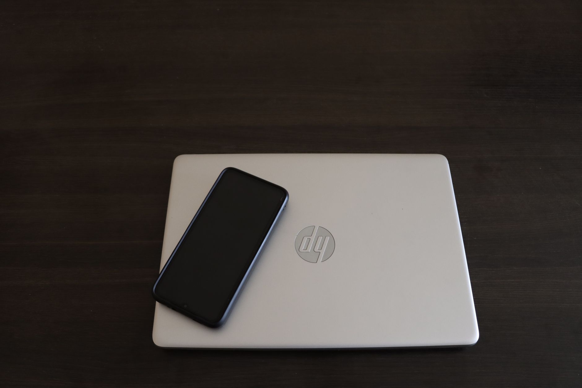 Como limpar o cache do celular do jeito certo Close-up of a smartphone resting on an HP laptop, symbolizing modern technology integration.