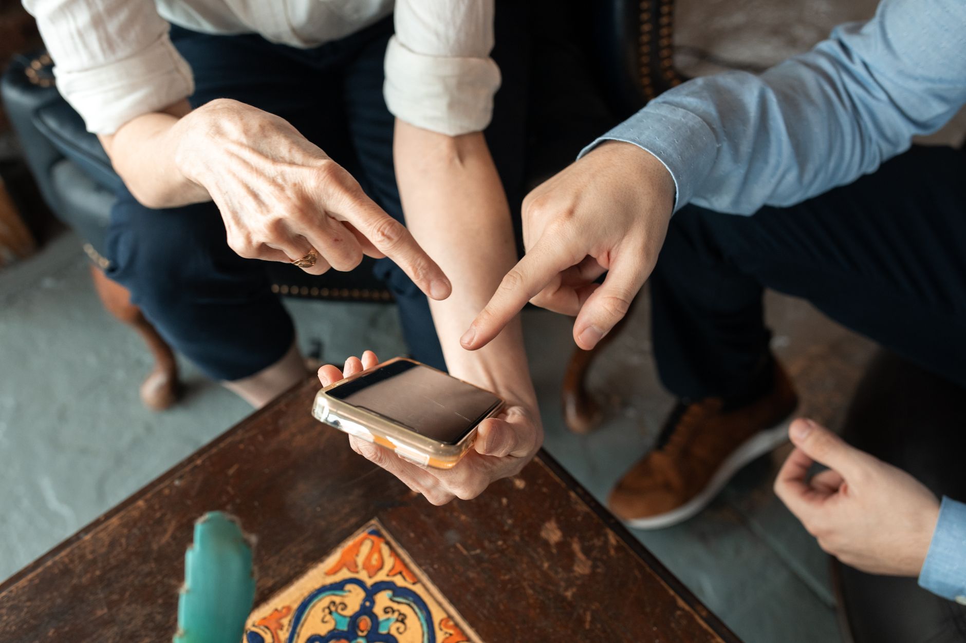 Celular pega vírus? Como proteger de verdade Two people engaged in discussion, pointing at a smartphone on a table indoors.