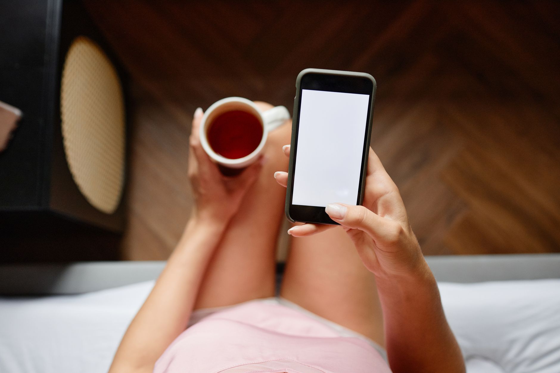 Como rastrear um celular Android perdido ou roubado Overhead view of a woman using a smartphone while holding a coffee cup indoors.