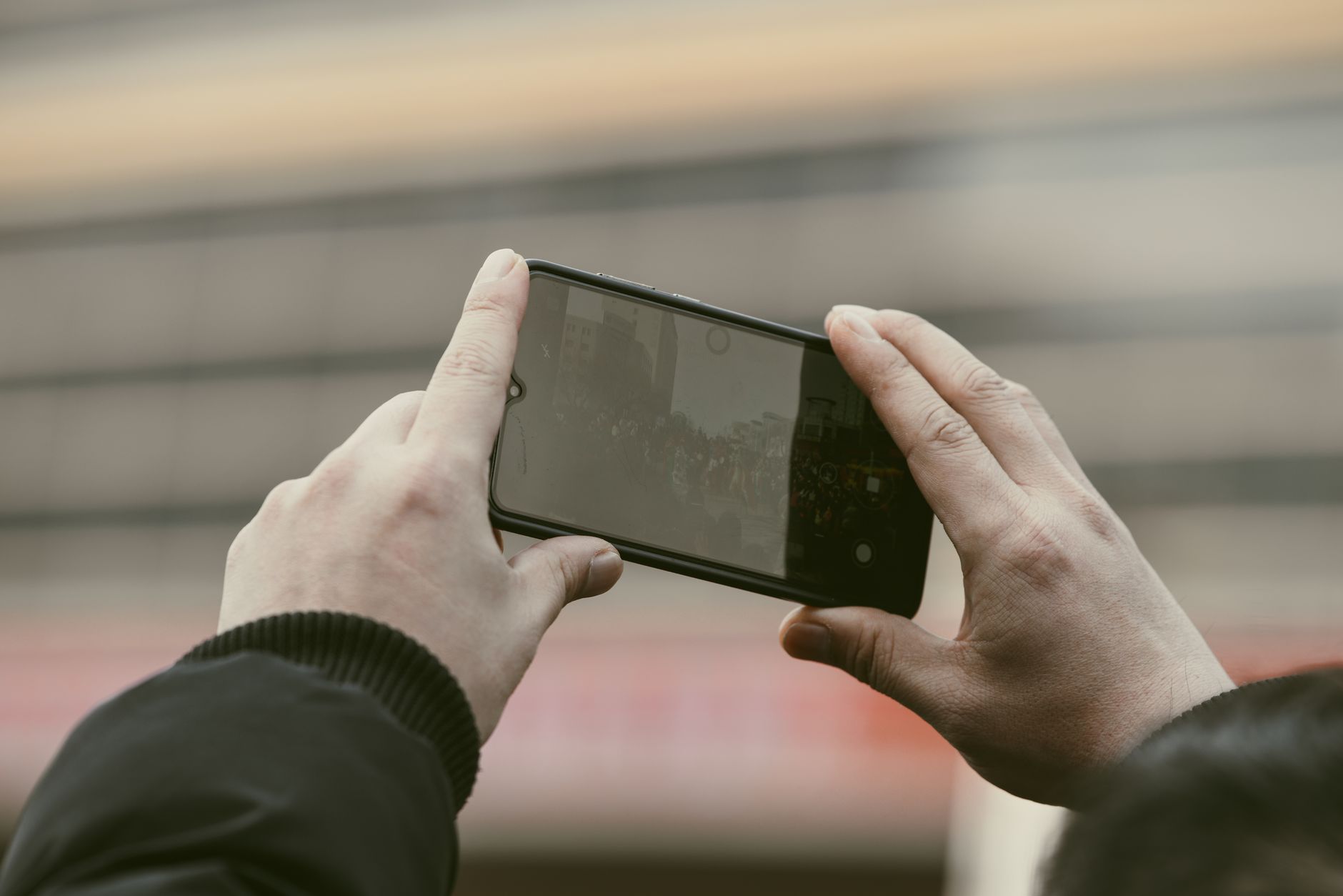 Como saber se um celular é original ou falsificado Close-up of hands using a smartphone to capture a photo outdoors.