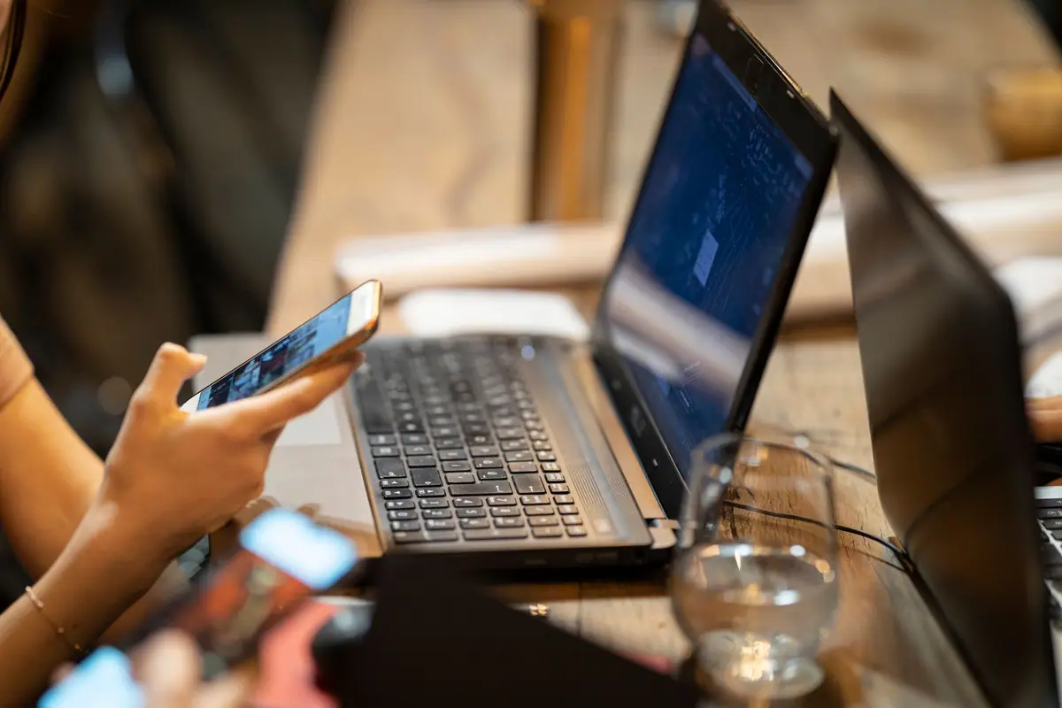 Pessoa usando smartphone e notebook em um ambiente de trabalho aconchegante