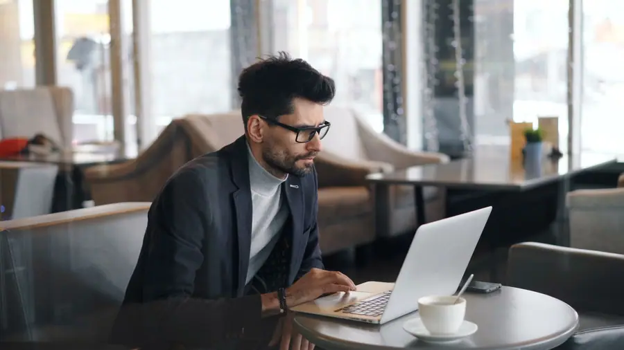 Homem trabalhando em um notebook em uma cafeteria Homem trabalhando em um notebook em uma cafeteria