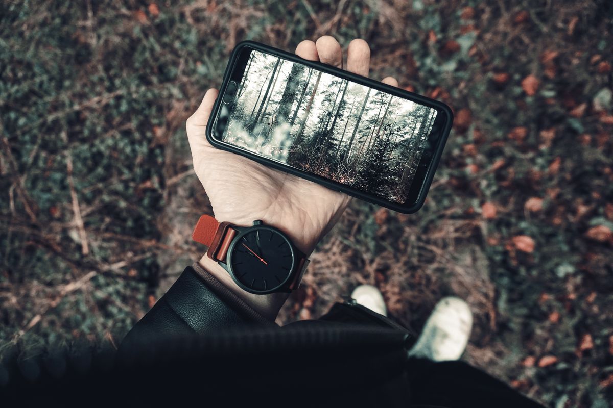 Mão segurando smartphone exibindo a tela de bloqueio em um ambiente externo iluminado
