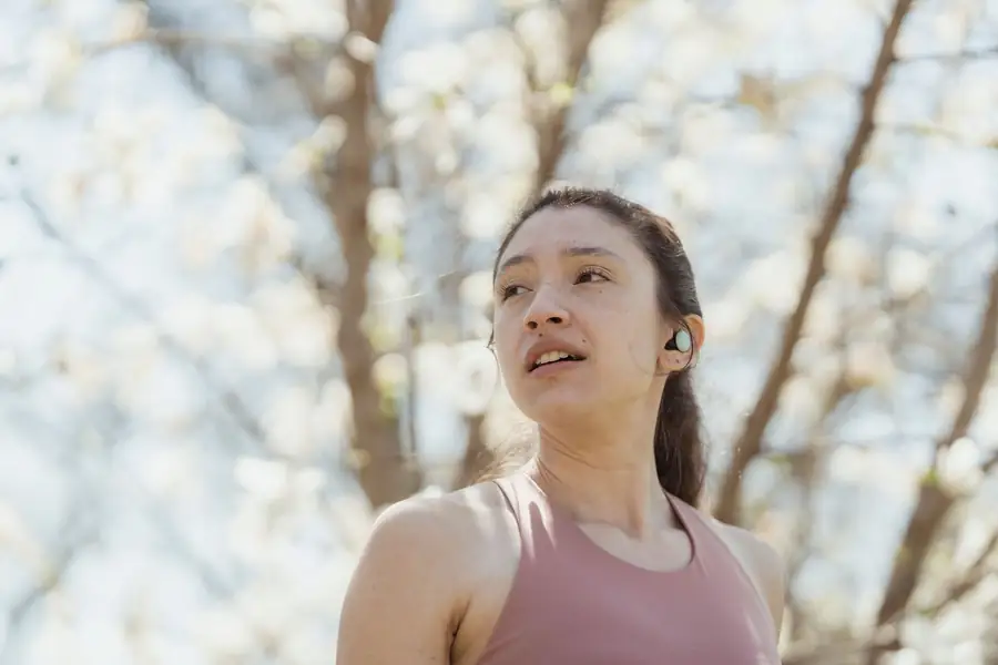 Mulher correndo em um parque com fones de ouvido sem fio Mulher correndo em um parque com fones de ouvido sem fio