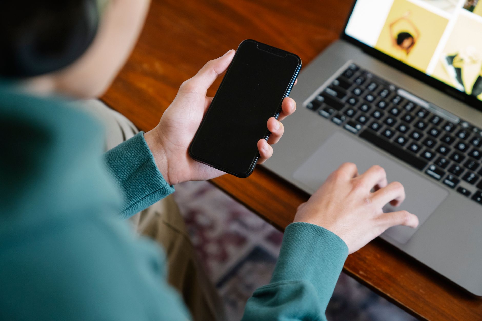 Pessoa comparando dois fones de ouvido ao lado de um celular sobre uma mesa.