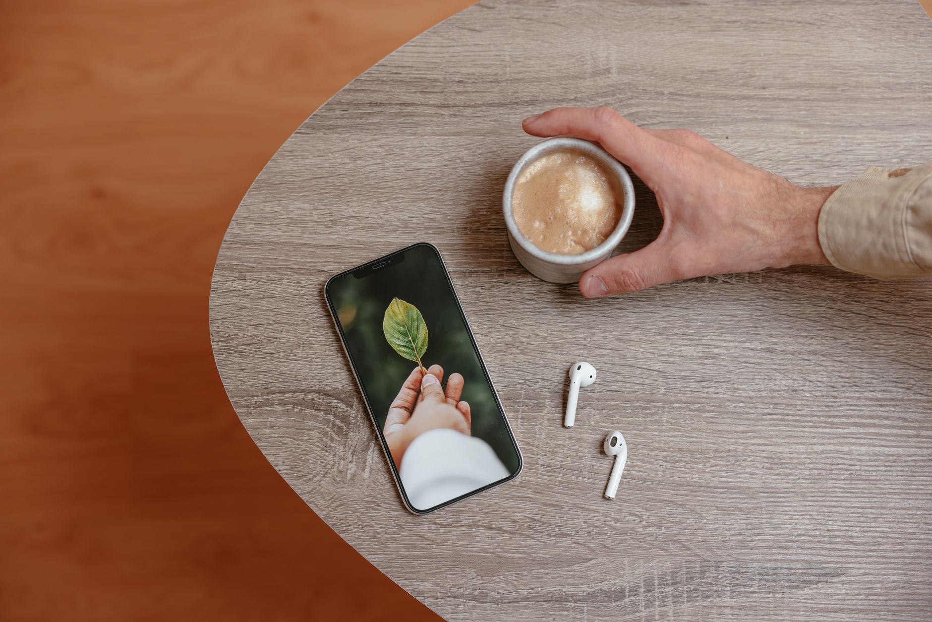 Stylish workspace with coffee, smartphone, and earphones on a wooden desk. Ideal for lifestyle or tech themes.
