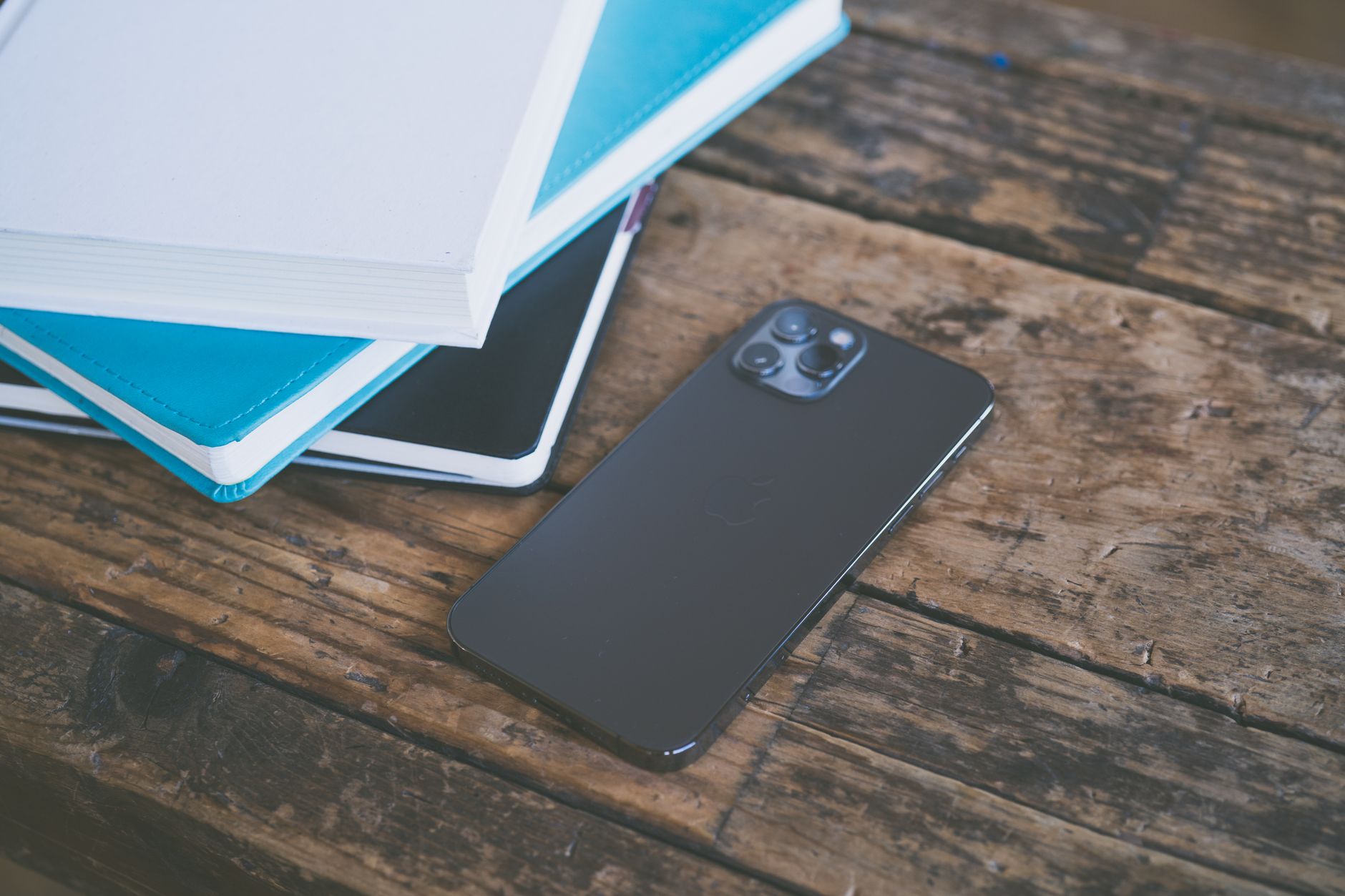 Como escolher entre um celular dobravel Flip ou Fold A modern smartphone placed beside assorted notebooks on a rustic wooden surface