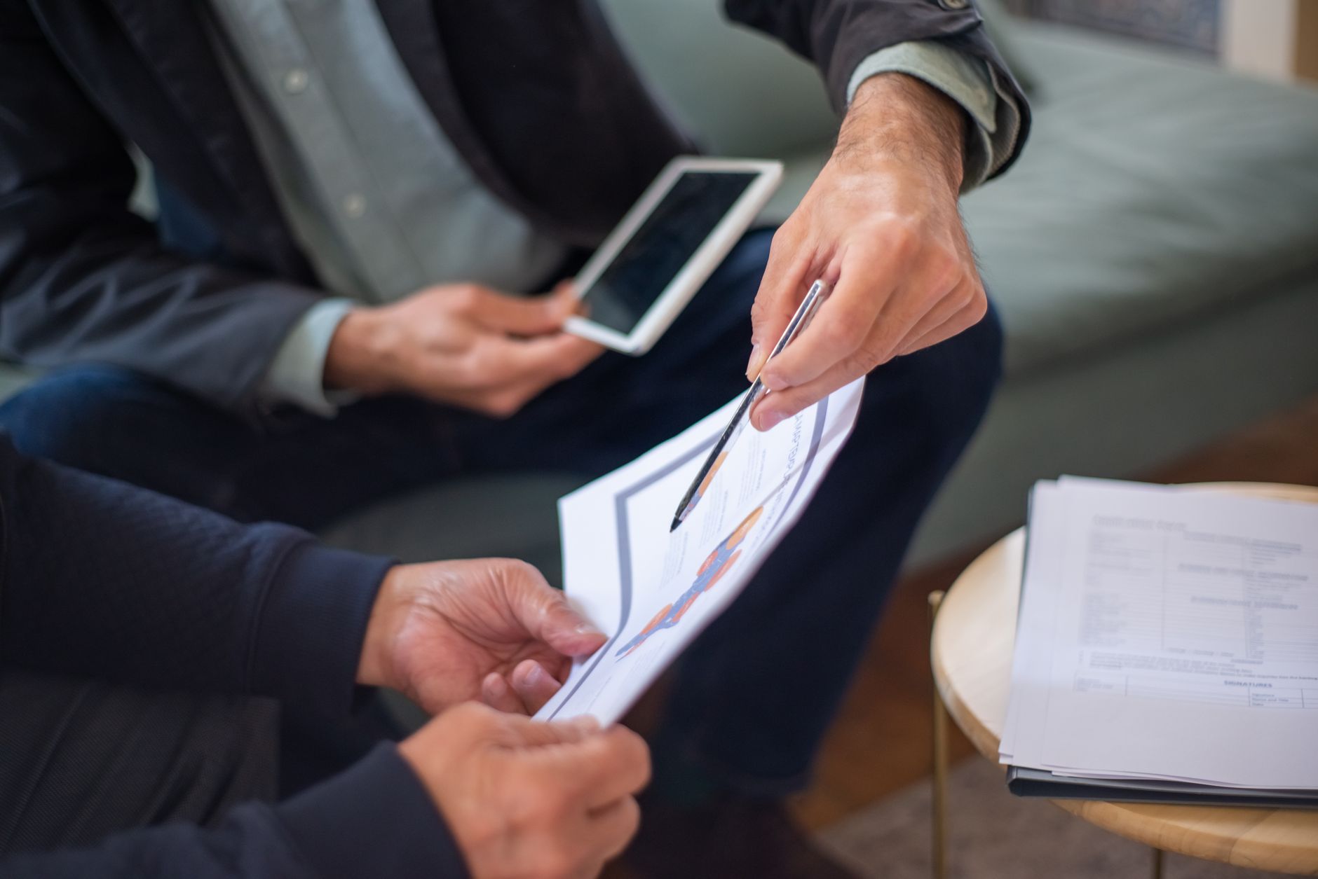 Garantia estendida de celular vale a pena? Close-up of two business professionals discussing documents in a meeting.
