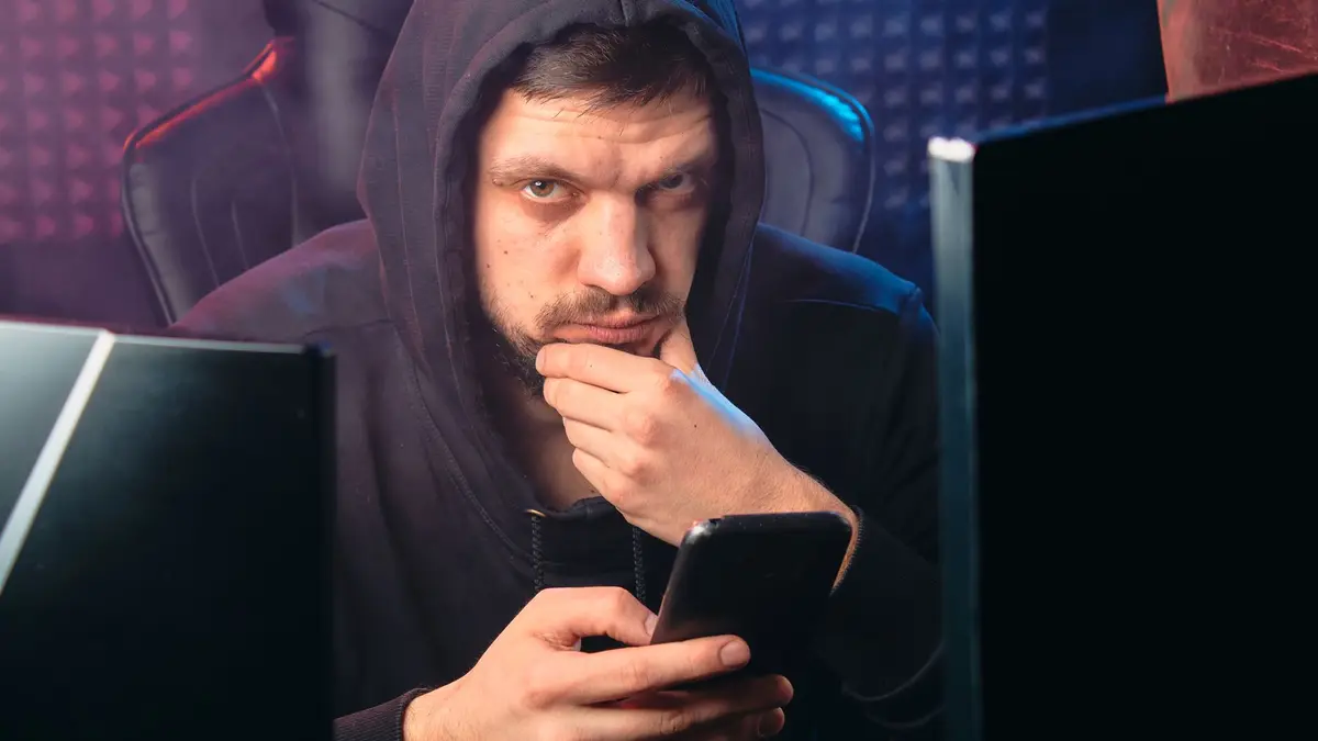 Homem de capuz olhando a tela de um celular