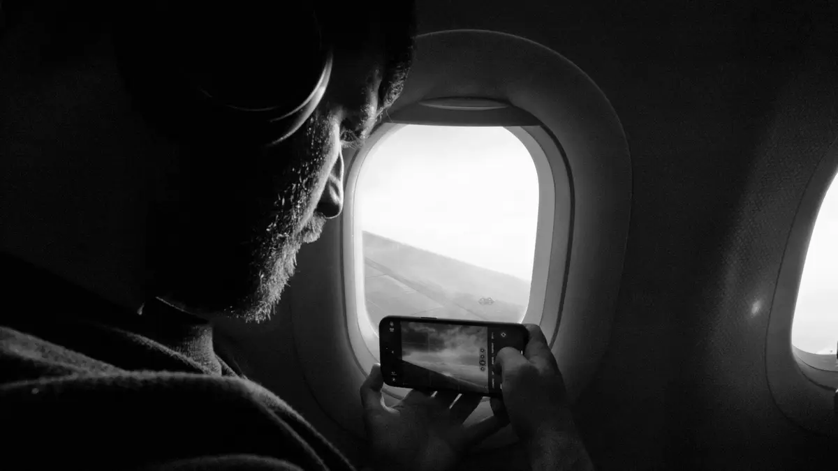 Passageiro fotografando pela janela do avião com o celular