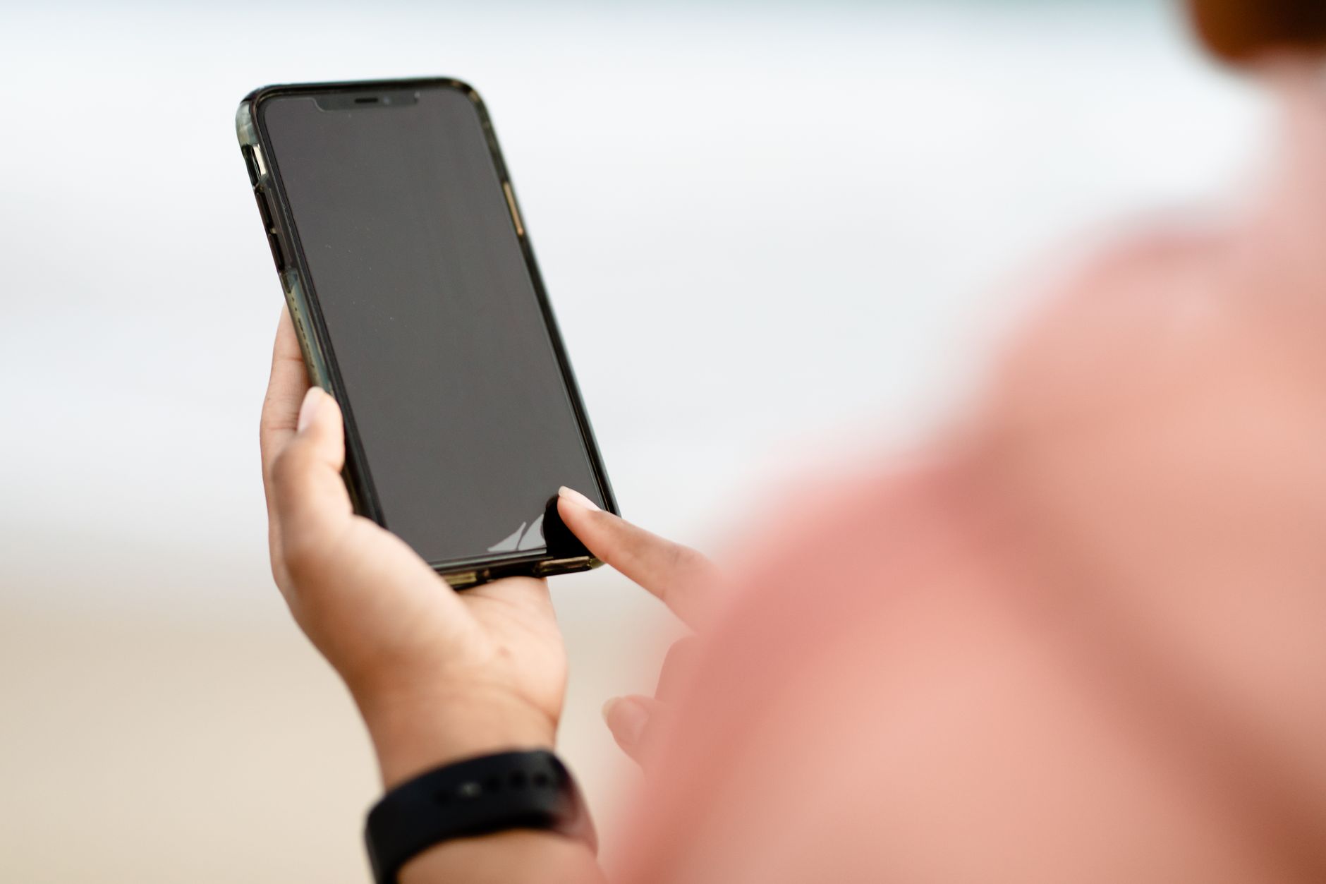 Modo retrato: como funciona e como usar sem erro A hand interacting with a smartphone touchscreen outdoors. Modern technology concept.