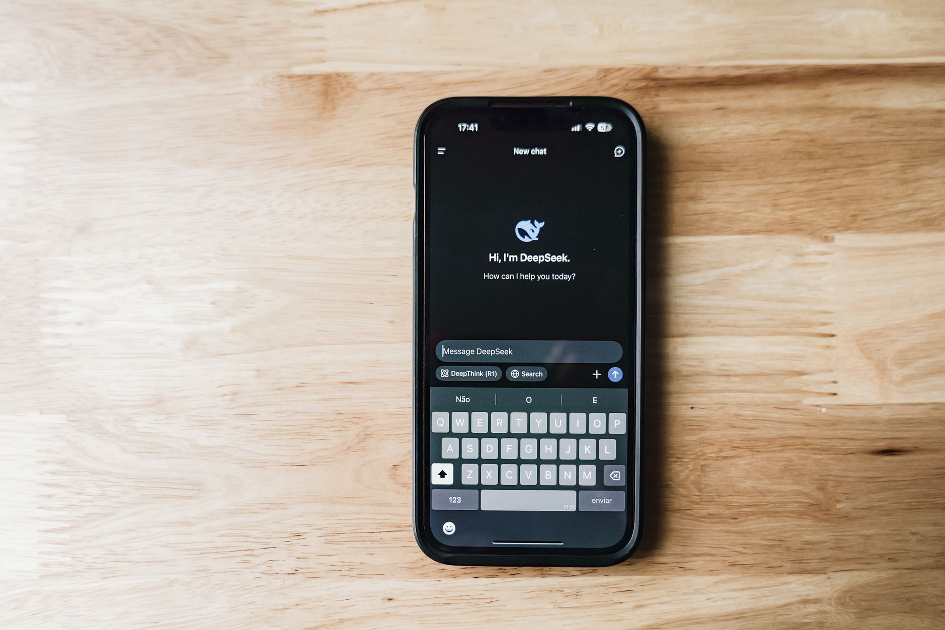 O que é chipset e por que ele define tudo no celular A smartphone on a wooden table showing an AI chatbot interface called DeepSeek.