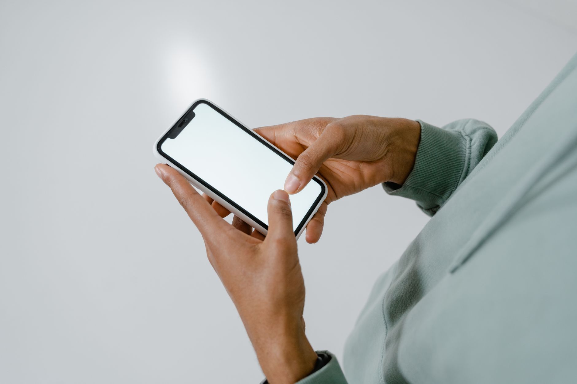 Pessoa comparando películas de proteção ao lado de um celular sobre uma mesa