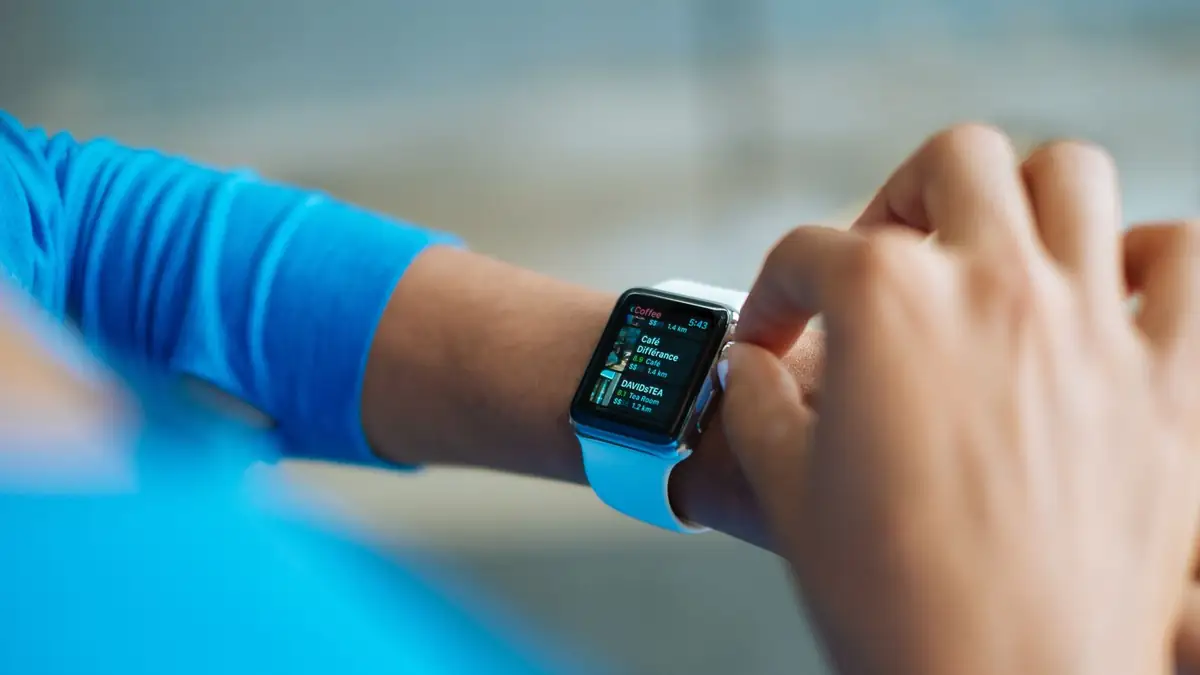 Pessoa interagindo com um smartwatch que exibe um aplicativo de atividade física