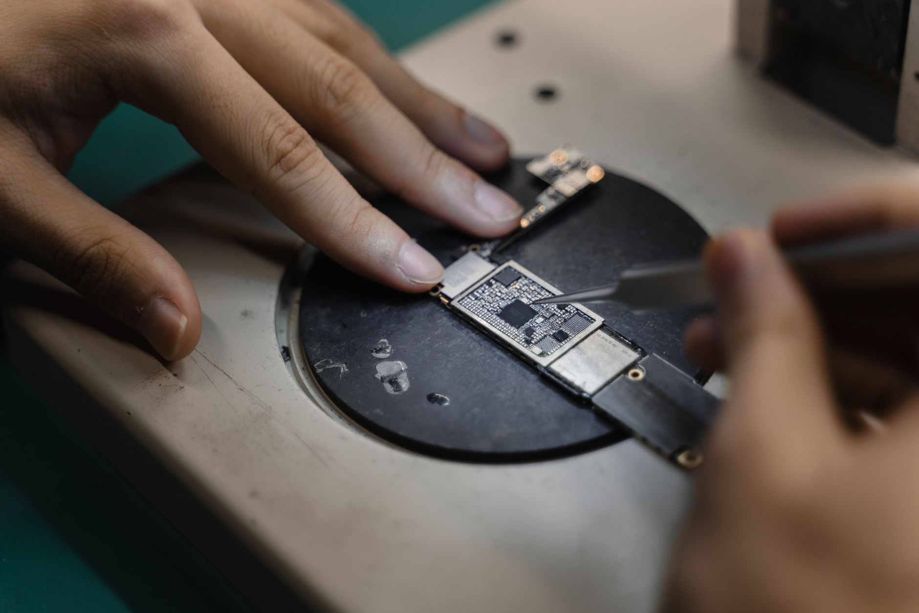 Quanto custa trocar a tela do celular? Detailed view of hands soldering electronic components, showcasing precision in engineering.