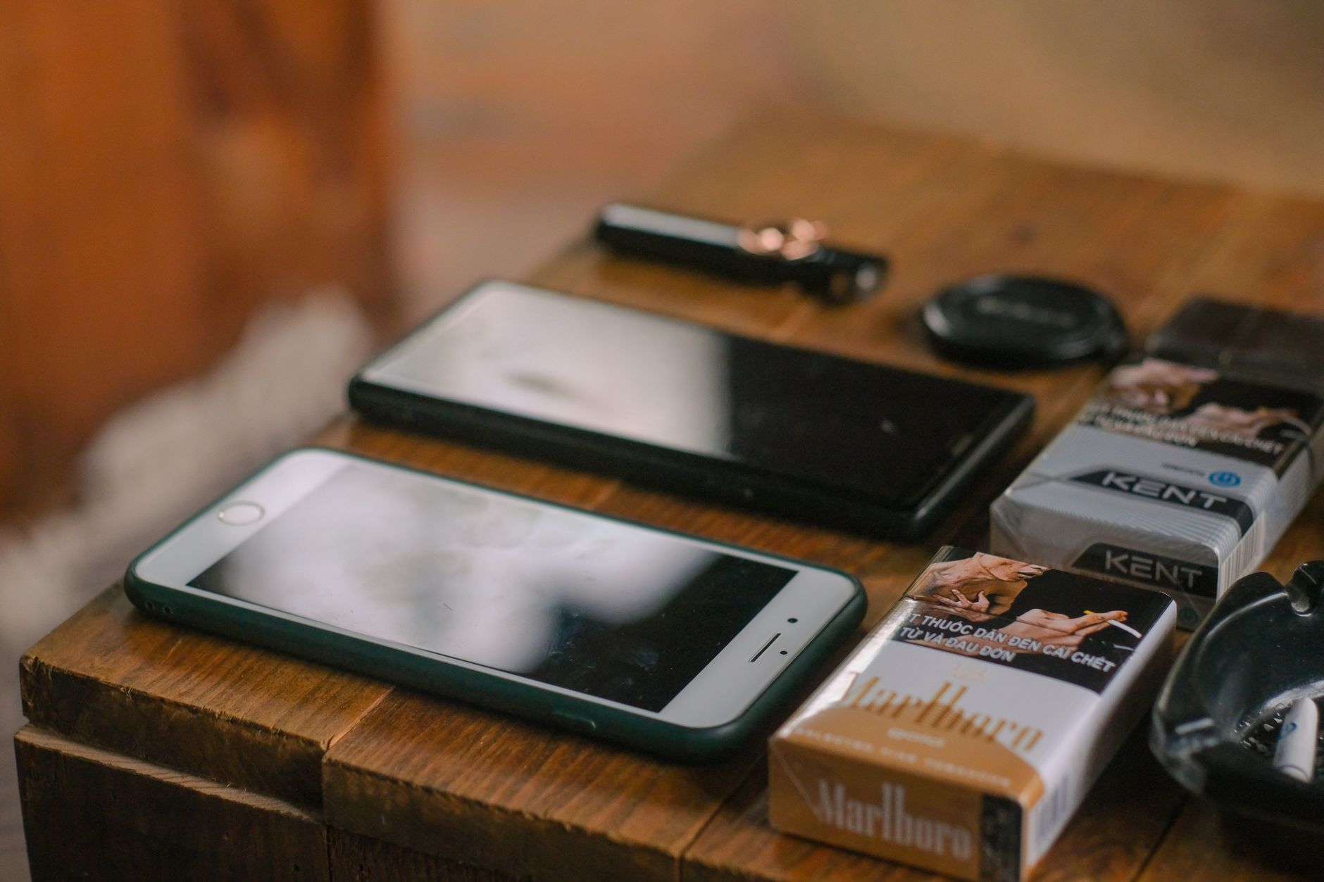 Como escolher o som do celular: mono ou estéreo Close-up of mobile phones, cigarette packs, and gadgets on a wooden table.