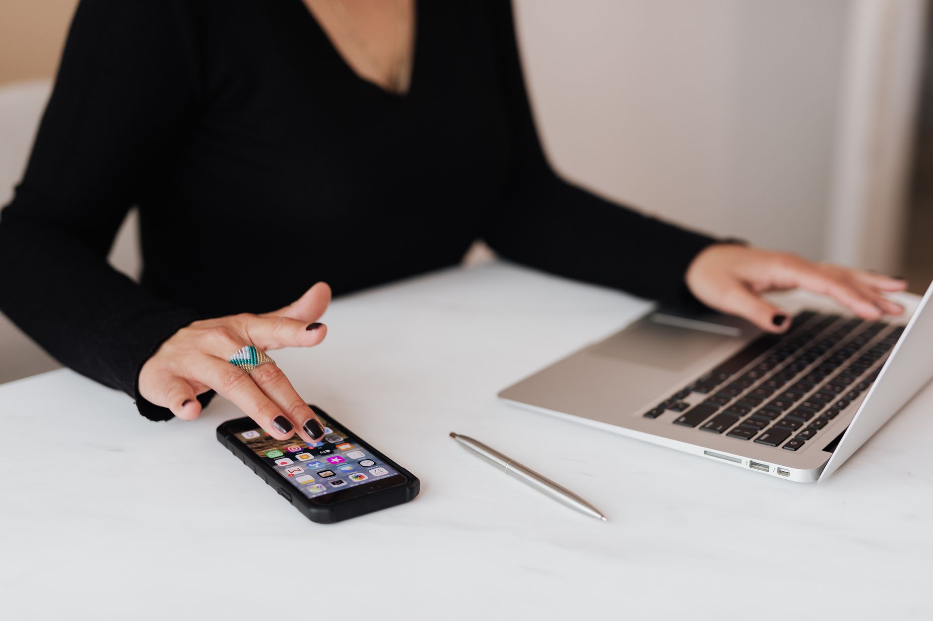RAM virtual no celular funciona ou é só marketing? Crop unrecognizable female in black sweater browsing smartphone while working on laptop in light office space