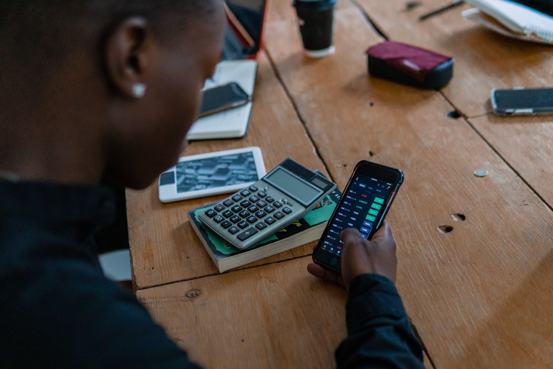 Pessoa comparando dois celulares sobre uma mesa antes de escolher um aparelho
