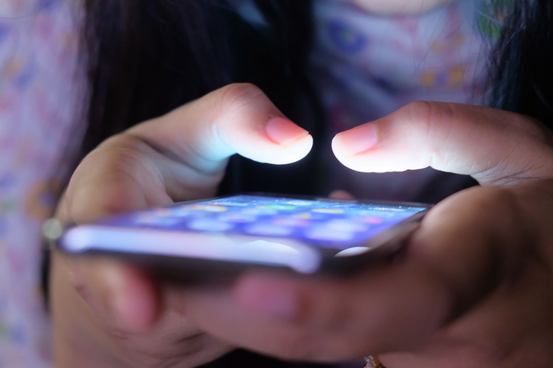 Como escolher entre versões do Moto G85 A close-up shot of hands holding a smartphone in low light, showcasing a glowing screen.