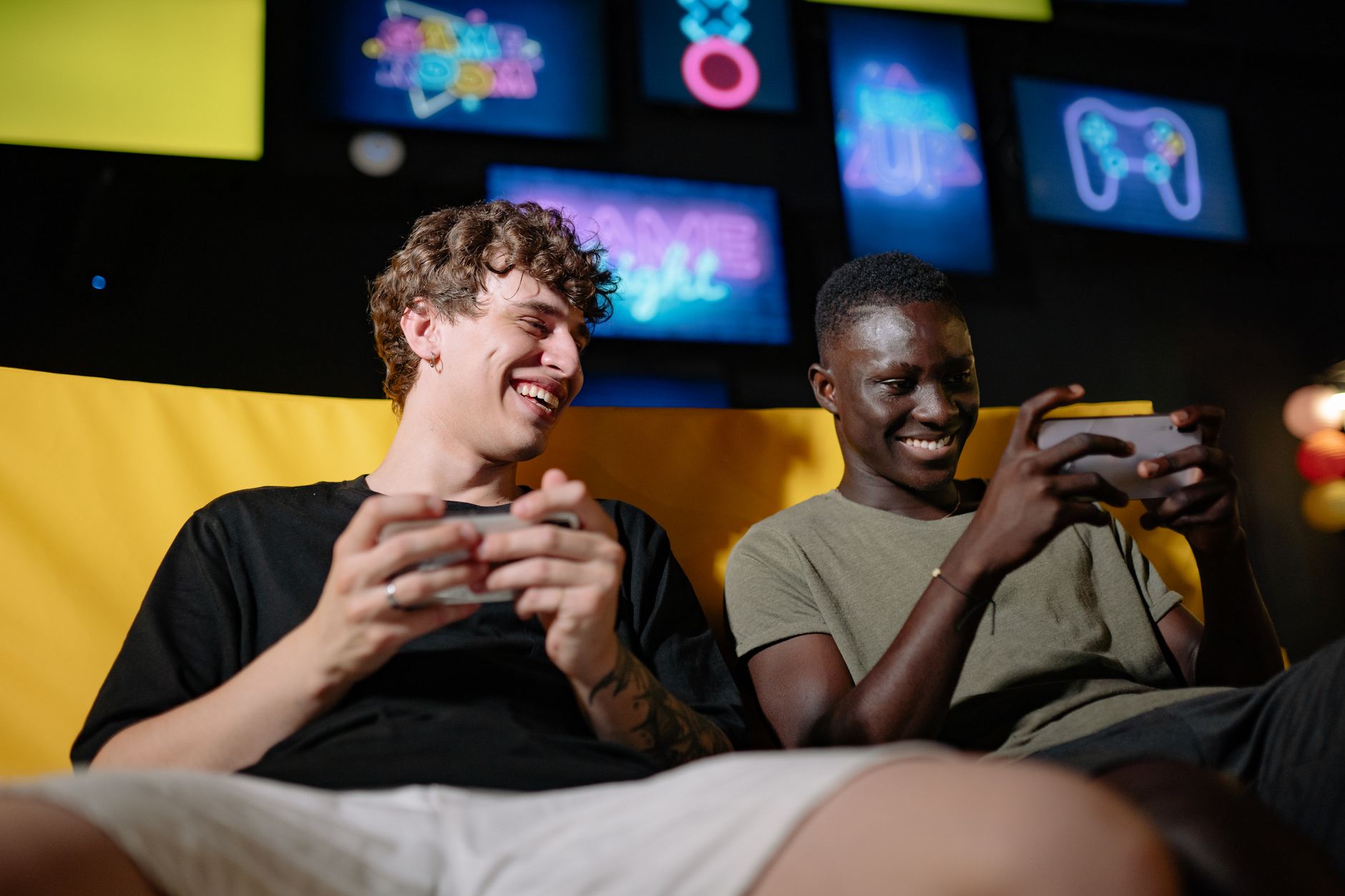 Snapdragon ou MediaTek: qual é melhor de verdade? Two happy young men sitting together enjoying mobile gaming indoors.
